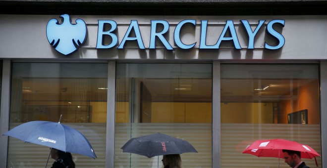 Varias personas con sus paraguas pasan por delante de una oficina de Barclays en el centro de Londres. REUTERS/Stefan Wermuth