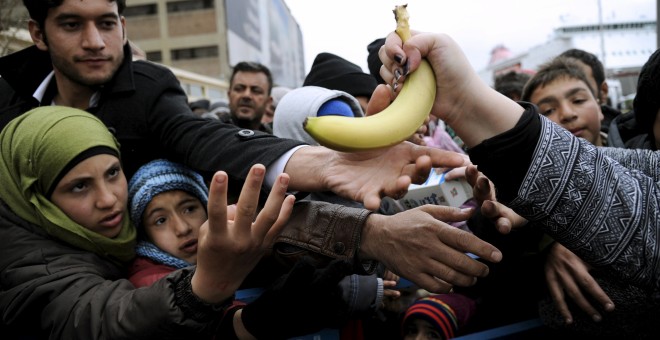 Migrantes y refugiados reciben alimentos de varios voluntarios en el puerto del Pireo (Grecia). - REUTERS