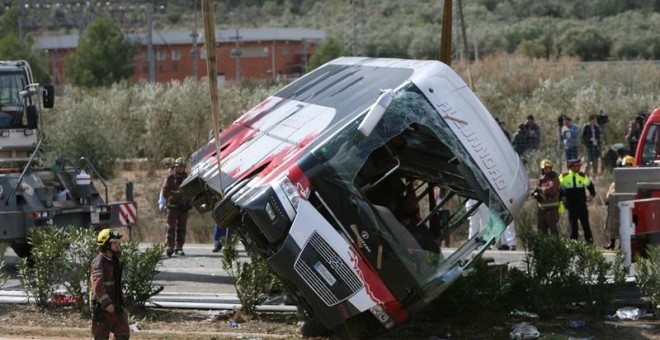 Efectivos del cuerpo de bomberos en el momento de levantar el autocar perteneciente a la empresa de Mollet del Vallès (Barcelona), que esta mañana ha chocado contra un vehículo en la autopista AP-7, a la altura de Freginals (Tarragona). Trece chicas de va