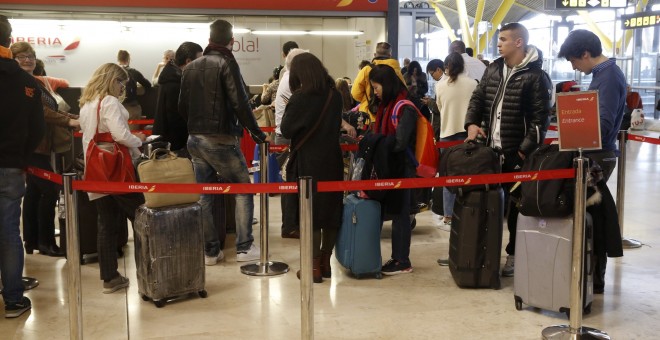 Varias personas esperan ser atendidas en el mostrador de Iberia de la T-4 del aeropuerto Adolfo Suárez Madrid-Barajas, donde los doce vuelos previstos con destino Bruselas han sido cancelados, tras las dos explosiones que han provocado el cierre del aerop