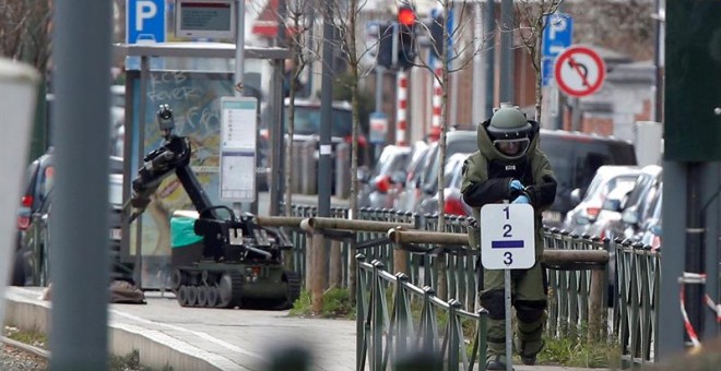 Un artificiero belga controla un vehículo robótico que se acerca a un artefacto sospechoso en la escena de la operación antiterrorista. EFE/Olivier Hoslet