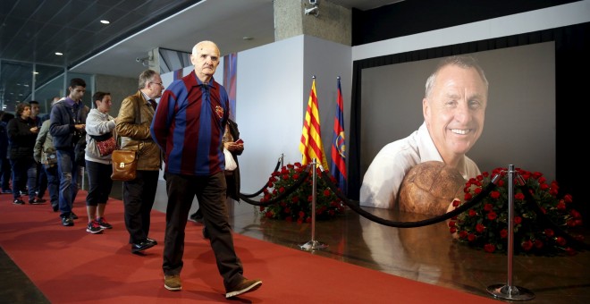 Los aficionados barcelonistas pasan por la foto de Johan Cruyff en el memorial instalado en el Camp Nou. REUTERS/Albert Gea