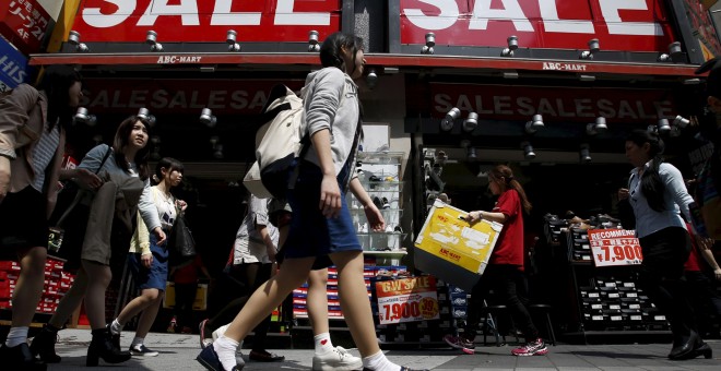 Varias jóvenes pasan por delante de una tienda de Tokio que anuncia rebajas. REUTERS/Yuya Shino