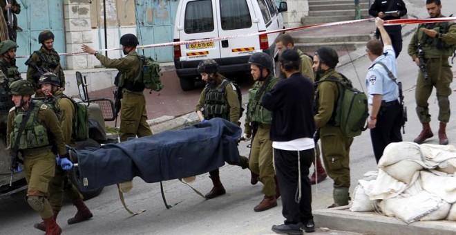 Soldados israelíes trasladan los cadáveres de los dos palestinos abatidos el 25 de marzo en Hebrón. / EFE