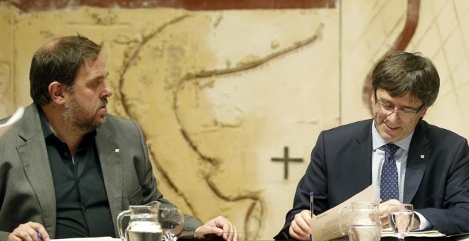 El presidente de la Generalitat, Carles Puigdemont, conversa  con el vicepresidente ,Oriol Junqueras, durante la reunión semanal del ejecutivo catalán./ EFE