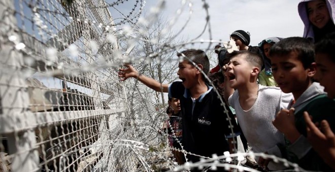 Varios niños en frente de la alambrada de las frontera de Macedonia en el campo improvisado de refugiados de Idomeni. - EFE