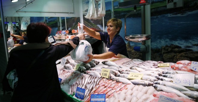 Una mujer haciendo la compra en una pescadería de un mercado de Madrid. REUTERS