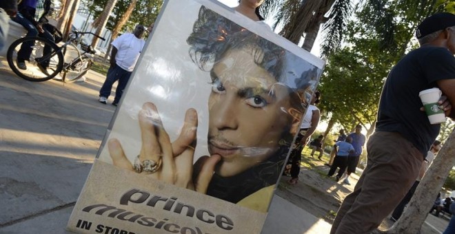 Una fan del fallecido músico estadounidense Prince sostiene un cartel con su imagen. EFE/MIKE NELSON