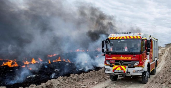 Un camión del cuerpo de bomberos pasa junto a los neumáticos que arden en Seseña, Toledo. EFE/Ismael Herrero