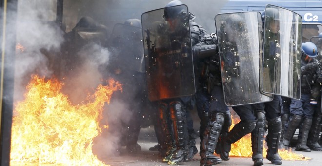 Gendarmes franceses, entre llamas provocadas por un grupo de encapuchados en París, durante las protestas contra la reforma laboral.- REUTERS