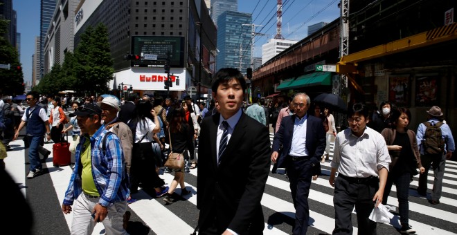 Varias personas cruzan una calle en el barrio de negocios de Tokio. REUTERS/Thomas Peter