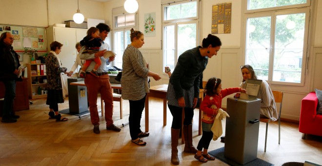 Ciudadanos suizos hacen cola para votar en el referendum sobre el establecimiento de una renta básica mensual. REUTERS/Ruben Sprich