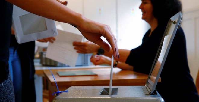 Un cudadano suizo deposita su voto en el referendum sobre el establecimiento de una renta básica mensual. REUTERS/Ruben Sprich