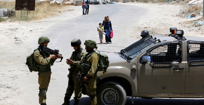Soldados israelíes vigilan la entrada a la ciudad palestina de Yatta. REUTERS/Mussa Qawasma