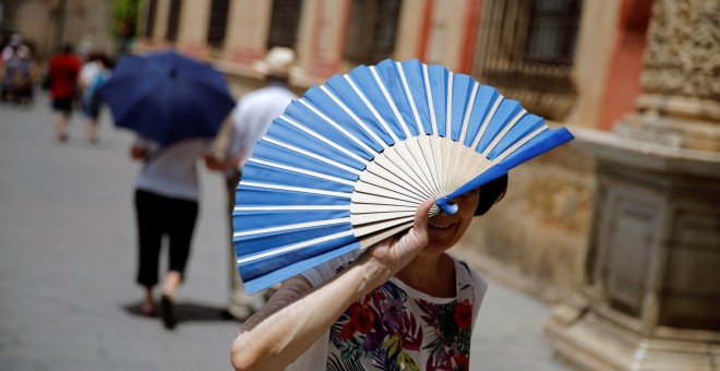 Una mujer se cumbre del sol con su abanico en una calle de  Sevilla. REUTERS/Marcelo del Pozo