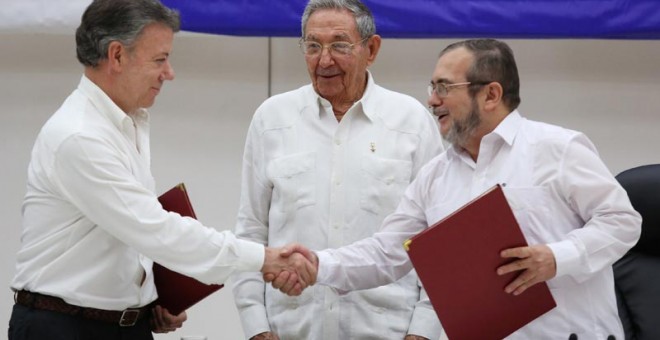 De izquierda a derecha, Juan Manuel Santos, presidente de Colombia, estrecha la mano del líder guerrillero Rodrigo Londono, más conocidad por su nombre de guerra, 'Timochenko'. Todo ello ante el presidente de Cuba, Raúl Castro. / REUTERS