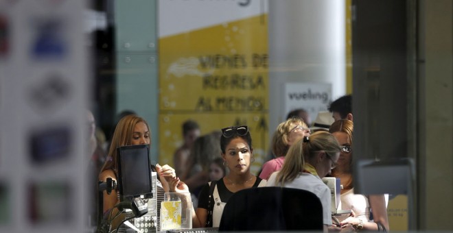 Personal de facturación de Vueling atiende a los viajeros en el Aeropuerto de El Prat. EFE