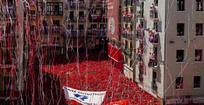 Miles de personas muestran en alto el tradicional 'pañuelico' rojo en la Plaza del Ayuntamiento de Pamplona durante el lanzamiento del chupinazo. / VILLAR LÓPEZ (EFE)