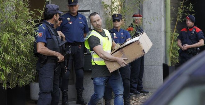 Mossos d'Esquadra y Policía Nacional transportan cajas con pruebas incautadas hoy en una operación en Barcelona en la que se prevé detener a once personas acusadas de blanquear 10 millones de euros vinculados al crimen organizado con la compra de inmueble