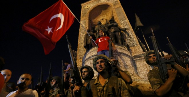 Militares turcos hacen guardia en la Plaza Taksim de turquía mientras ciudadanos turcos ondean la bandera del país. REUTERS/Murad Sezer