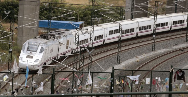Un tren Alvia similar al accidentado en Angrois, pasa por la curva donde todavía permanecen objetos colocados en memoria de las 80 víctimas mortales. EFE