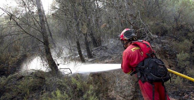 Un miembro de la UME refresca zonas quemadas en el perímetro del incendio de la Sierra de Espadán que ya ha quemado 1.400 hectáreas y ha sufrido hoy un pequeño rebrote en uno de sus frentes, a pesar de que la lluvia y el menor calor han aliviado algo las