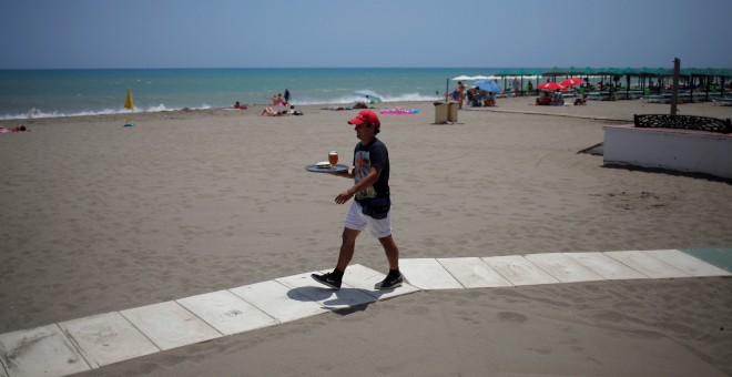 Un camarero sirve una cerveza en un bar en la playa de Torremolinos (Málaga). REUTERS/Jon Nazca