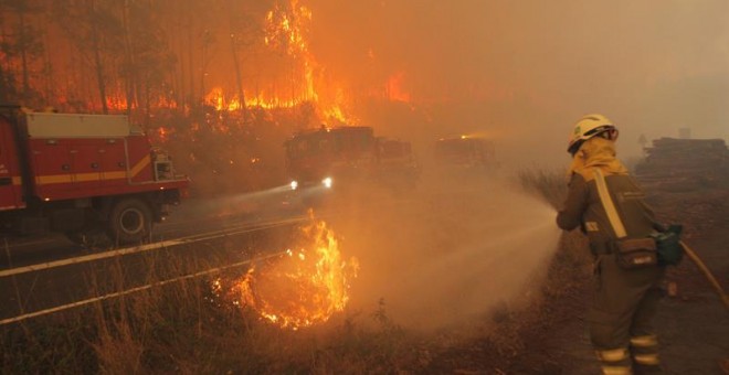 Un bombero muy cercano al fuego intenta apagarlo con una manguera en Santiago de Compostela/EFE