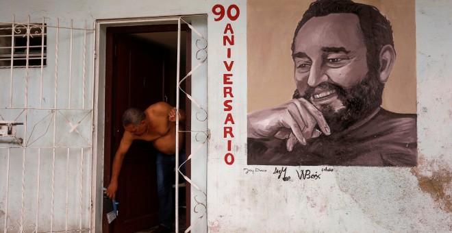 Un hombre en la puerta de su vivienda en La Habana, en cuya fachada tiene pintado un retrato de Fidel Castro. REUTERS/Stringer