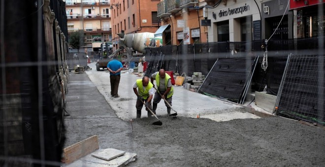 Dos hombres asfaltan una calle en Málaga/REUTERS