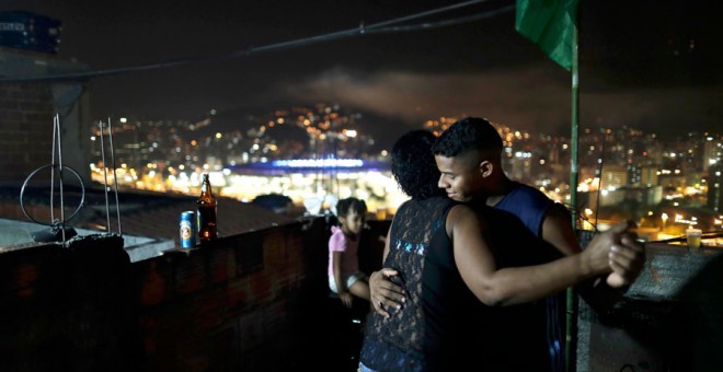 Dos personas bailan en la favela de la Maré con Maracaná de fondo el día de la inauguración. REUTERS/Ricardo Moraes