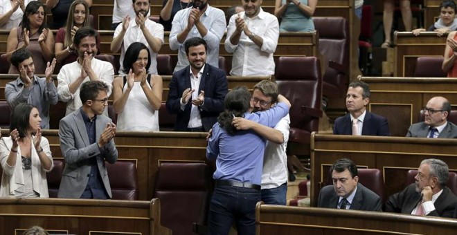 El líder de Podemos, Pablo Iglesias (de espaldas), abraza al portavoz de En Comú Podem, Xavier Domènech, tras su intervención en la segunda sesión del debate de investidura del líder del PP, Mariano Rajoy, esta mañana en el Congreso de los Diputados.- EFE