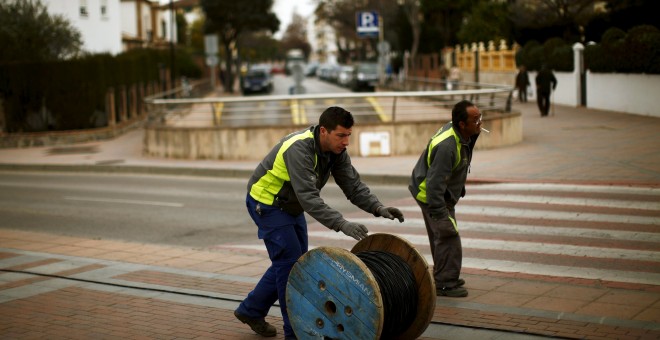 Dos trabajadores trasladan un rodillo de cable eléctrico en la localidad malagueña de Ronda. REUTERS / Jon Nazca