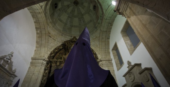 A hooded penitent of the 'Numeraria del Rosario' brotherhood waits for the start of the Santo Entierro procession at the San Domingos de Bonaval church, during Holy Week in Santiago de Compostela, northwestern Spain, on March 25, 2016. Christian believers
