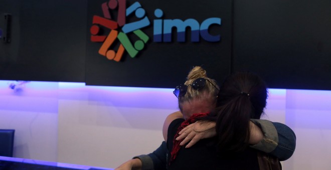 Dos trabajadores de IMC TV se abrazan justo después de que la Policía turca haya cerrado la redacción del canal. - REUTERS