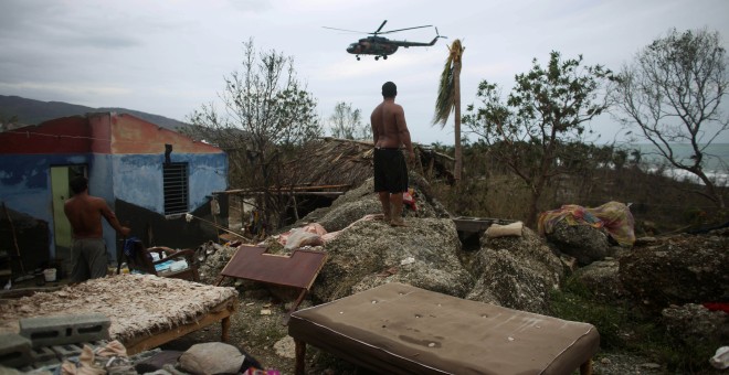 Un hombre observa un helicóptero en Cajobabo (Cuba) tras el paso del huracán Matthew. / ALEXANDRE MENEGHINI (REUTERS)