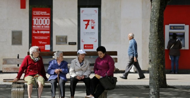 Varios pensionistas sentados en un banco cerca de una oficina bancaria en la localidad burgalesa de Briviesca. AFP / César Manso