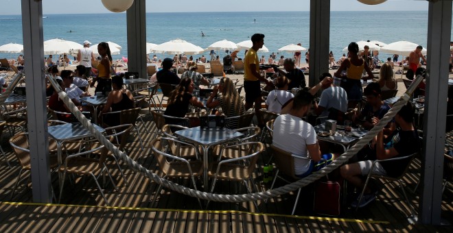 Turistas en un chiringuito en la playa de la Barceloneta, en Barcelona. REUTERS