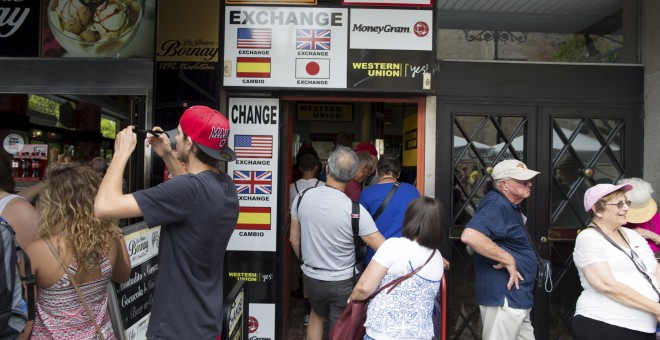 Turistas en uno oficina de cambio de moneda en Sevilla. REUTERS