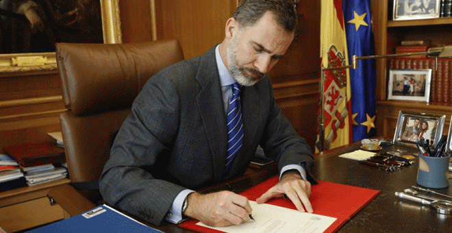 El rey Felipe VI firma, en su despacho del Palacio de la Zarzuela, el Real Decreto con el nombramiento de Mariano Rajoy.- EFE
