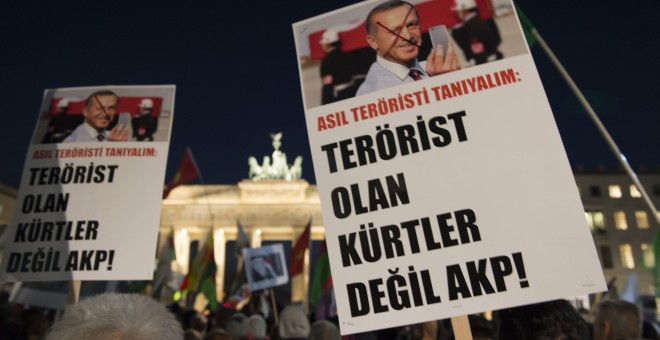 Manifestantes muestran pancartas en las que se lee 'Actualmente deberíamos conocer a los terroristas. No son los kurdos, pero del AKP' durante una protesta frente a la Puerta de Brandenburgo, Berlín (Alemania). / EFE