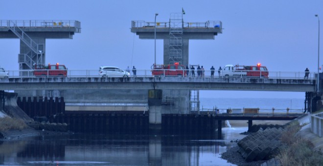 La gente vigila la desembocadura de un río después de que se emitieron avisos de tsunami provocados por un terremoto, en Iwaki, prefectura de Fukushima. REUTERS