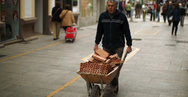 Un trabajador acarrea una carretilla con ladrillos en Ronda (Málaga). REUTERS
