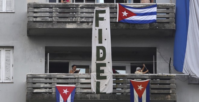 Banderas y un cartel con el nombre Fidel Castro cuelgan desde la fachada de un edificio, este jueves en la La Habana (Cuba). REUTERS