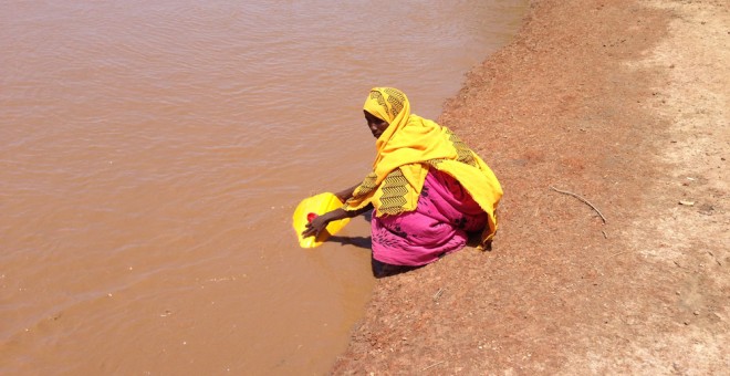 Mujer recogiendo agua en un río en Burkina Faso. / AUARA