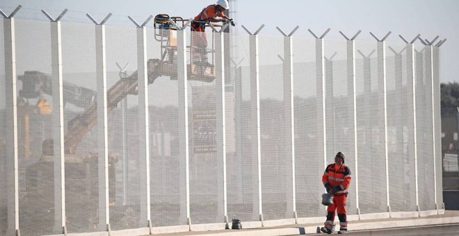 Operarios franceses colocan alambres de púas en una valla del puerto de Calais. /  REUTERS