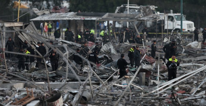 Agentes de Policía caminan por los escombros de las casetas destruidas por las explosiones en Tultepec (México). /REUTERS