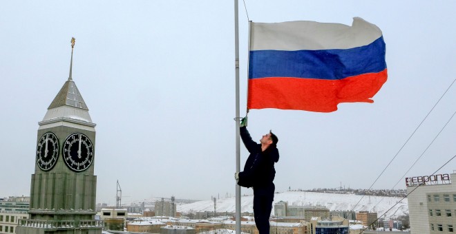 Un trabajador colo a media asta la bandera rusa en homenaje a las víctimas del accidente del avión Tu-154.- REUTERS