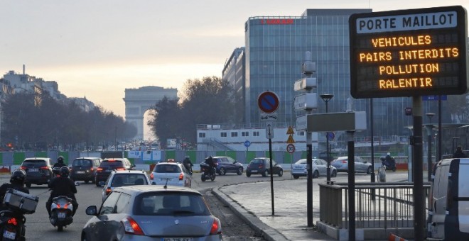 Vehículos transitan al lado de un cartel que anuncia las restricciones al tráfico en el centro de París por contaminación el pasado día 9. /AFP