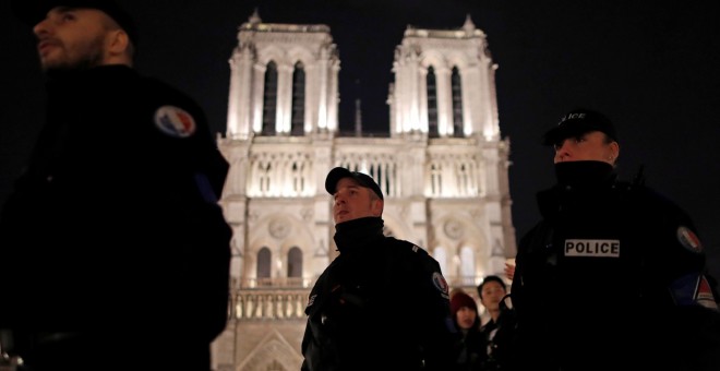 Varios agentes de la Policía francesa patrulla frente a la Catedral de  Notre-Dame, en París, la noche de Navidad. REUTERS/Christian Hartmann